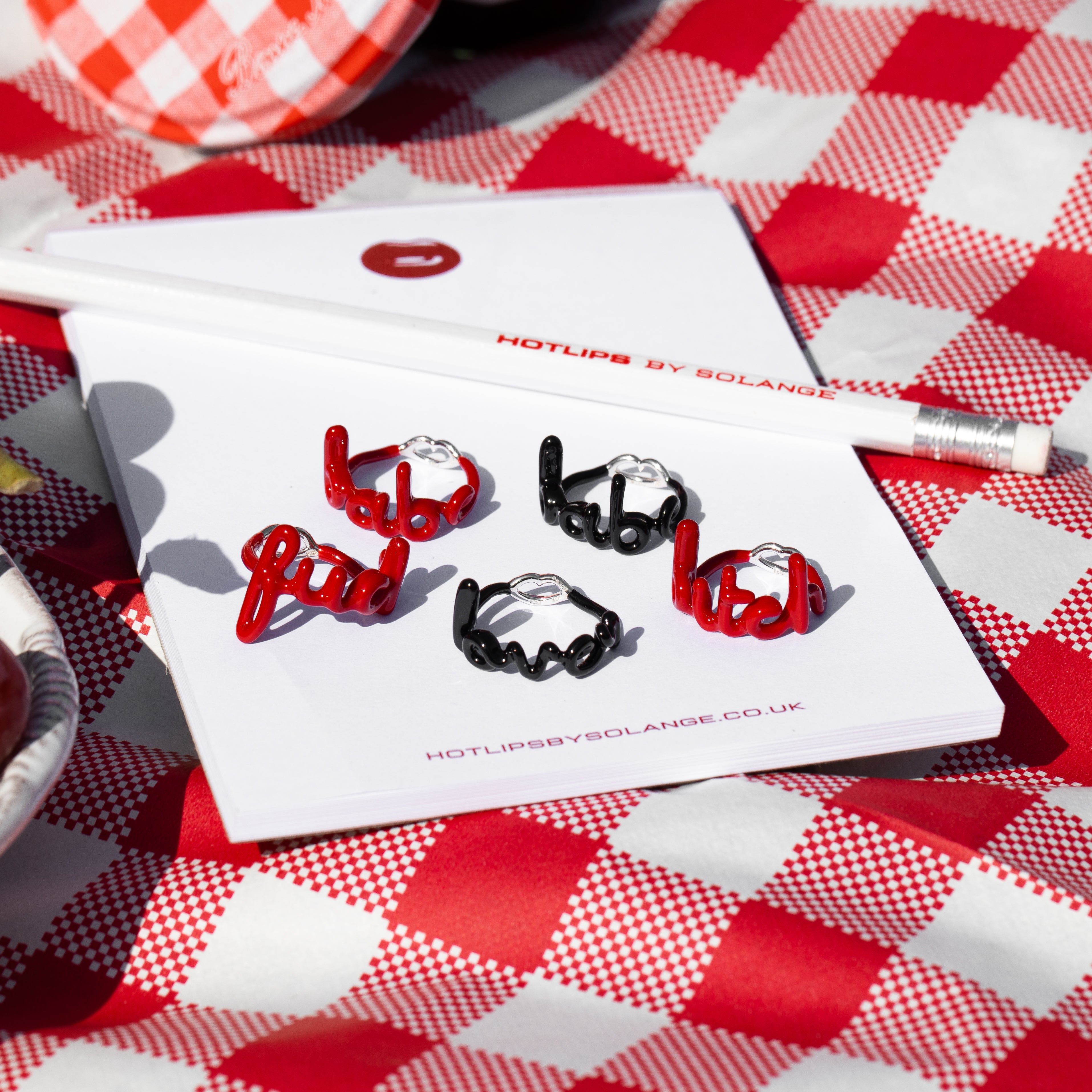 Babe Hotscripts silver and classic red enamel ring front view on note pads