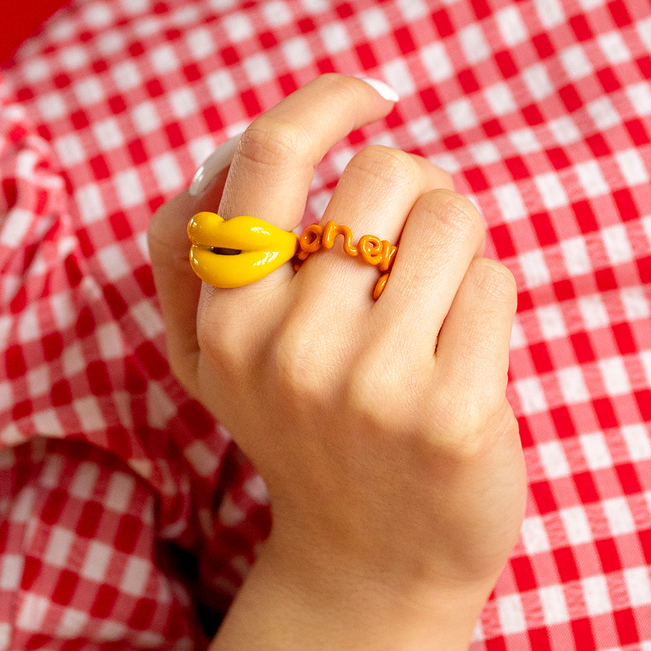 Honey Hotscripts enamel word ring and Banana Yellow Hotlips ring by Solange on model