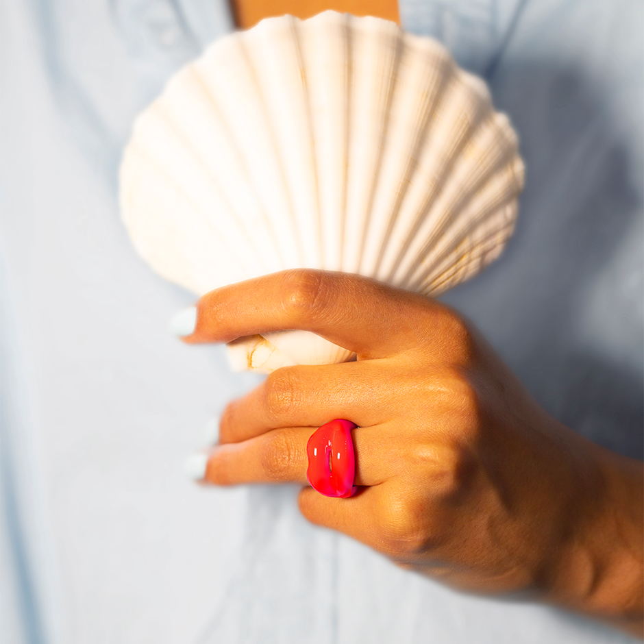 Neon Coral Hotlips Ring on hand with scallop shell