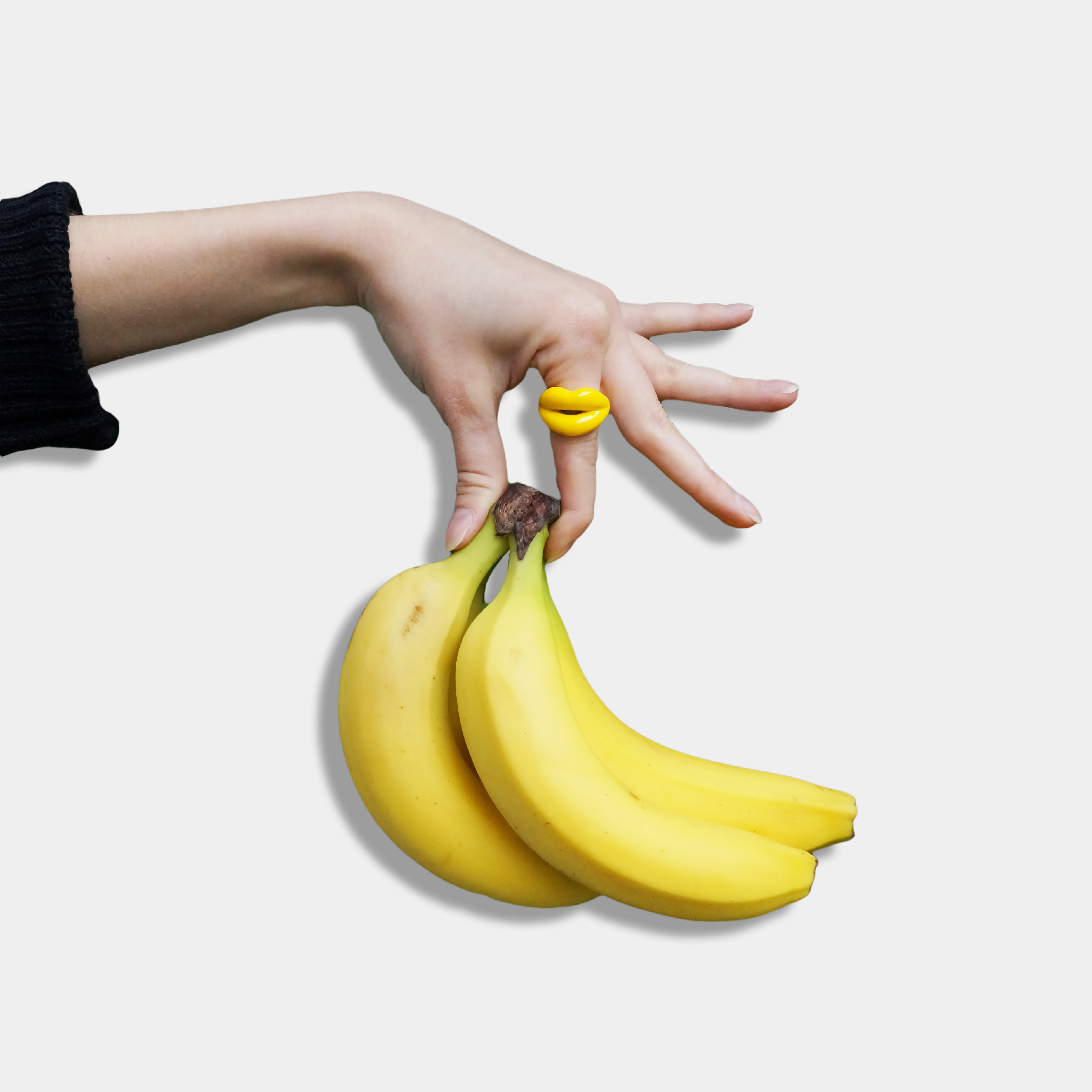 Banana Yellow Hotlips ring on hand holding a bunch of bananas