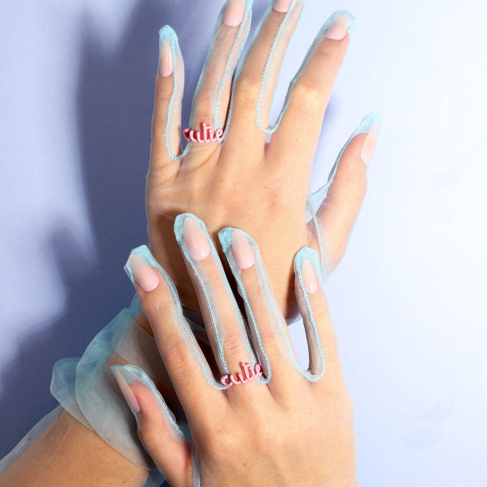 Cutie word Hotscript silver and pink enamel ring by Hotlips by Solange on hands wearing blue gloves