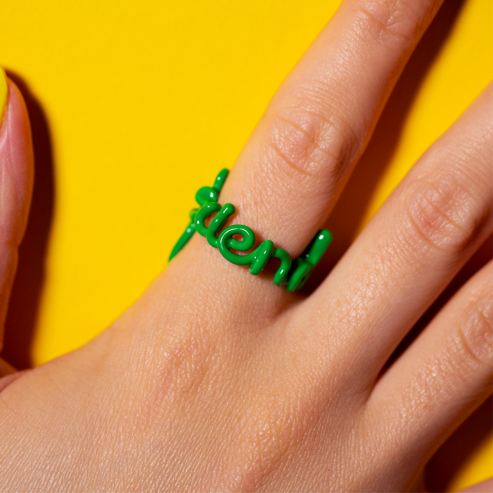 Friend green Hotscripts by Solange ring on hand yellow background