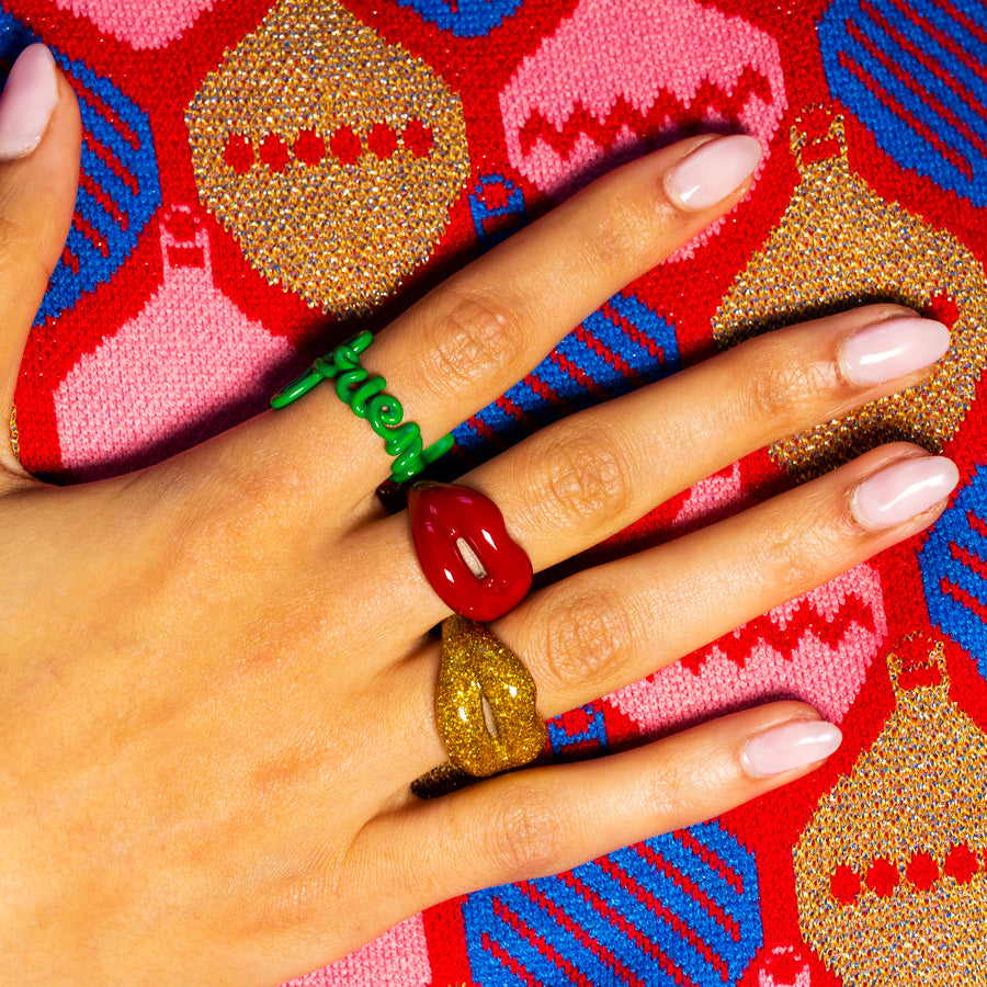 Friend classic red and glitter gold Hotscripts and Hotlips rings on hand Christmas jumper