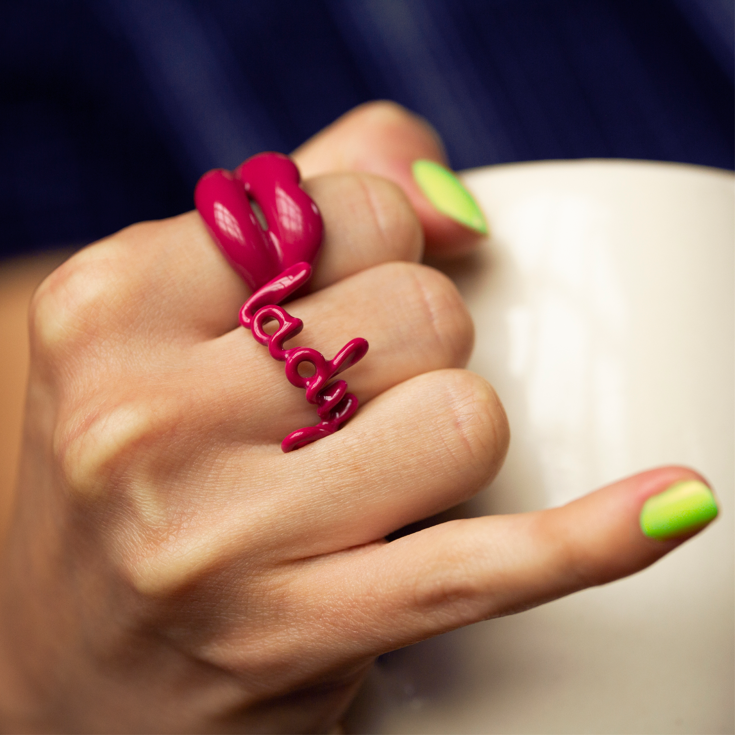 Lady pink enamel Hotscript word ring with dusky pink Hotlips ring on hand with upturned pinky