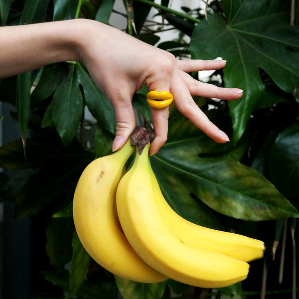 Banana Yellow Hotlips ring on hand holding a bunch of bananas